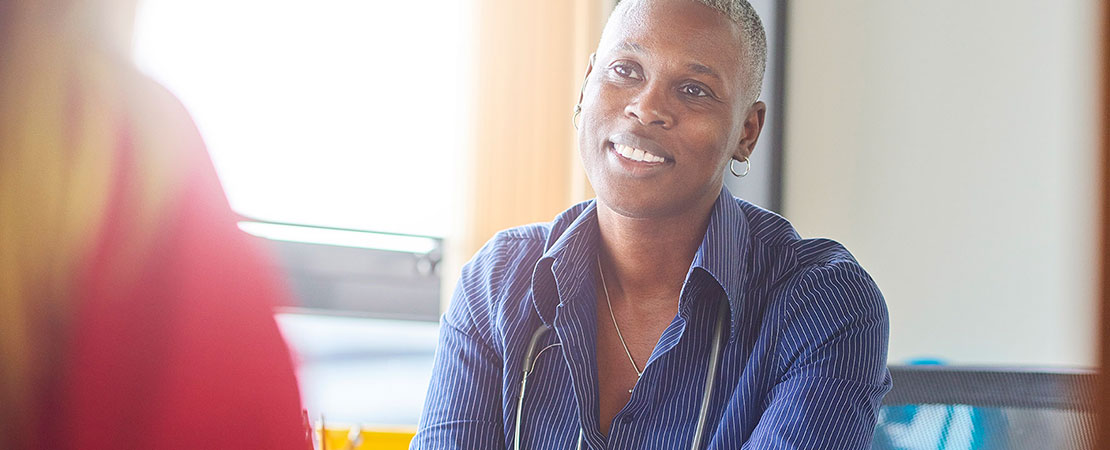 African American doctor talking with female patient at desk